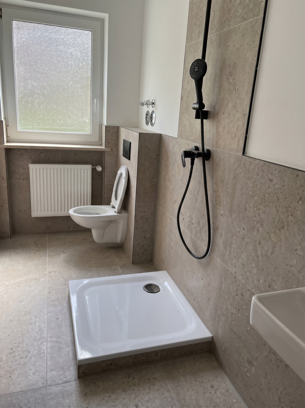 Fertiges Badezimmer mit bodengleicher Dusche und Steinoptik